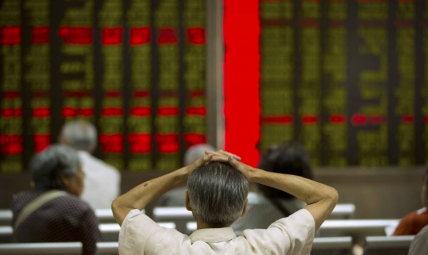 A Chinese investor monitors displays of stock information at a brokerage house in Beijing, Tuesday,...