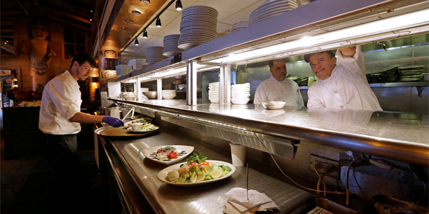 In this photo taken Monday, July 27, 2015, Arturo Ramirez, right reaches for plates stacked overhea...