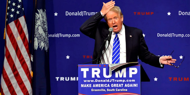 Republican presidential candidate Donald Trump pulls his hair back to show that it is not a toupee ...