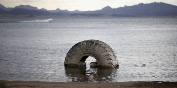 FILE - In this May 18, 2015, file photo, a partially submerged tire sits along the shore of Lake Me...