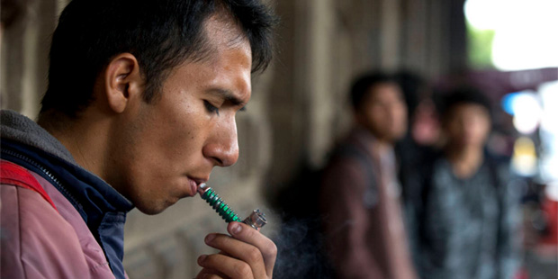 Marijuana legalization activists smoke in the portico of a government building across the street fr...