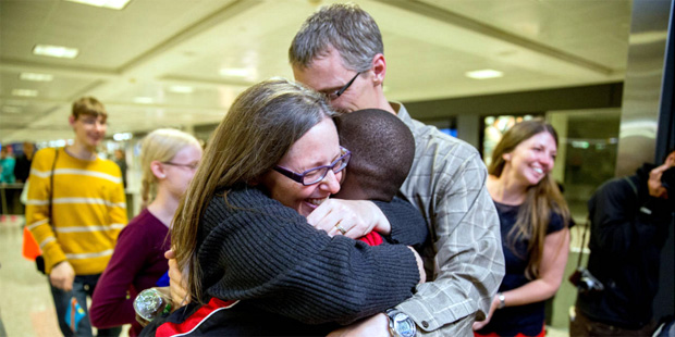 Jennifer and Eric Sands of Illinois hug their adopted son Issaac, 12, as he arrives from the Congo ...