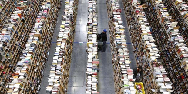 FILE - In this Dec. 2, 2013, file photo, Amazon.com employees work the shelves along the miles of a...