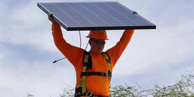 In this July 28, 2015, photo, electrician Adam Hall install solar panels on a roof for Arizona Publ...