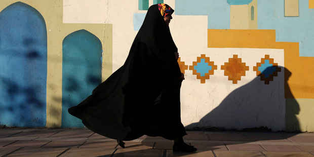 A head-to-toe veiled Iranian woman walks on  Enghelab-e-Eslami (Islamic Revolution) St. in Tehran, ...