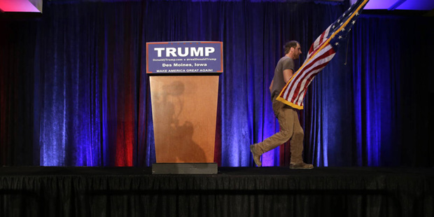 A worker walks off the stage as he takes the flag after Republican presidential candidate, business...