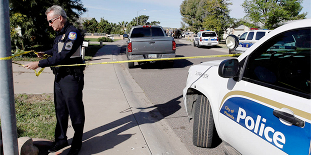A police officer puts up some tape at the scene of a house fire and fatal shooting Tuesday, Feb. 23...