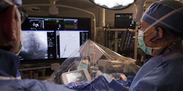 Cardiologist Timothy Byrne and his team look into the monitor while feeding a catheter into the hea...