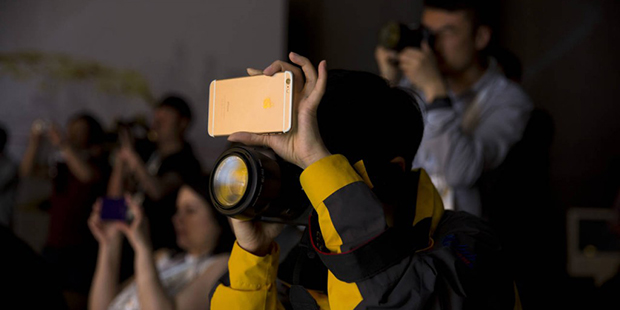 A woman uses a camera and a cellphone to record the unveiling of the Shell Concept Car in Beijing, ...