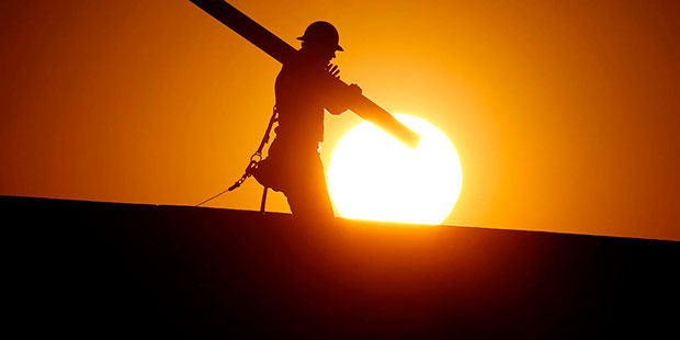 A home builder works at sunrise, Monday, June 20, 2016, in Gilbert, Ariz., in an effort to beat the...