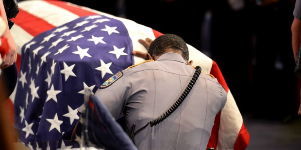 A member of Baton Rouge police Cpl. Montrell Jackson's unit kneels and touches his casket during hi...
