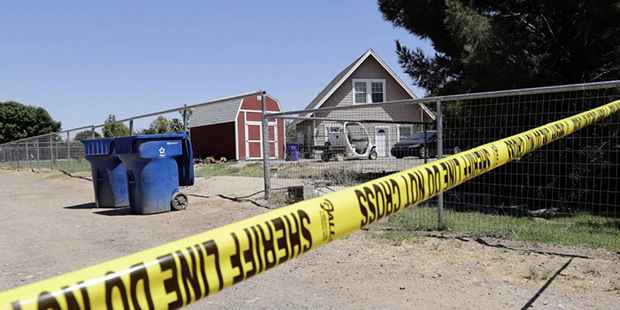 Crime scene tape blocks the entrance to a home where multiple bodies were found, Tuesday, July 26, ...