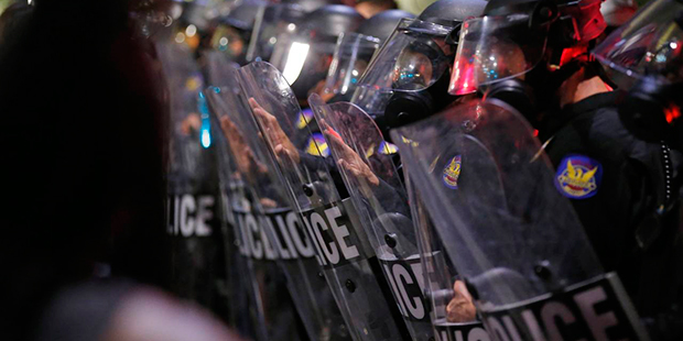 Police in riot gear block a street as hundreds of marchers take to the streets to protest against t...
