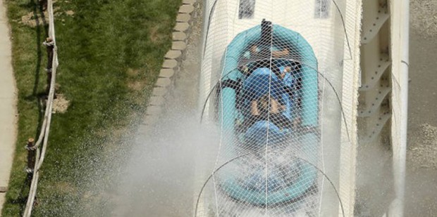 FILE - In this July 9, 2014 file photo, riders are propelled by jets of water as they go over a hum...