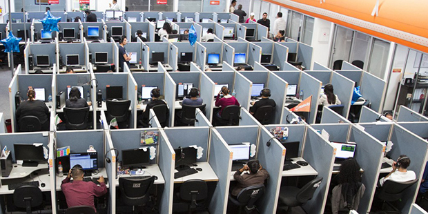 In this Aug. 13, 2014 photo, workers sit at desks at  Firstkontact Center, a call center in the nor...