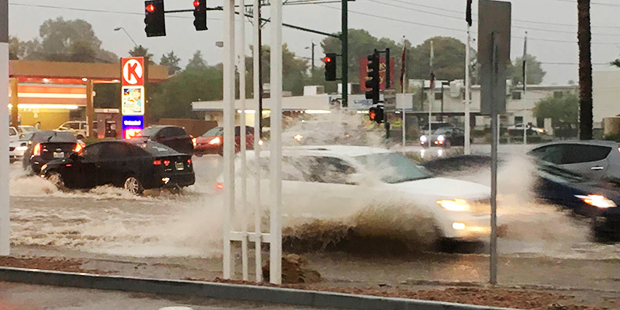 In this photo taken Tuesday, Aug. 2, 2016, cars make their way through a flooded intersection in Ph...