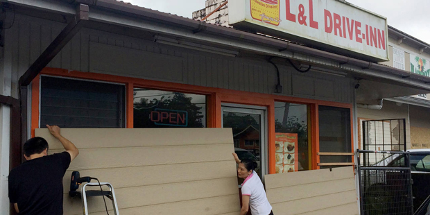 Kaly Sun, right, removes boards from her restaurant in Pahoa, Hawaii after Tropical Storm Madeline ...
