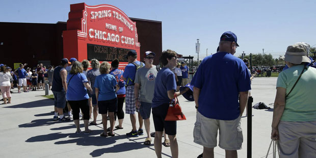 Fans line up to take pictures with a sign at Sloan Park before a spring training baseball game betw...