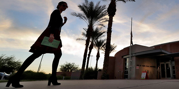 A voter carries in her mail in ballot to her polling station early, Tuesday, Nov. 8, 2016, in Tempe...