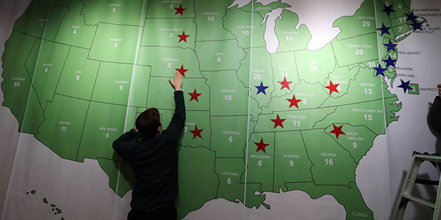 A man puts a sticker on an electoral map during an election watch event hosted by the U.S. Embassy ...