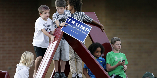Children climb on a sculpture as Republican presidential candidate Donald Trump speaks during a ral...