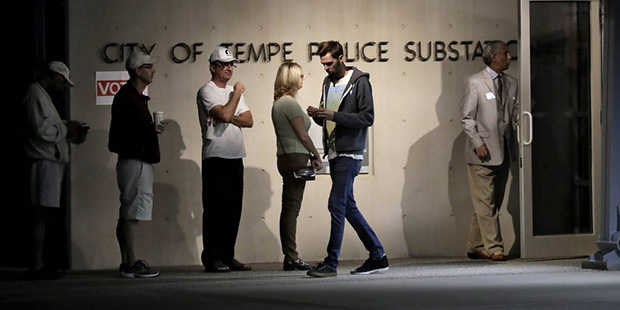 Voters wait to vote as a voter exits his polling station, Tuesday, Nov. 8, 2016, near Phoenix. (AP ...
