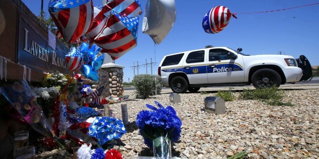 A Phoenix Police Department squad SUV parks next to a makeshift memorial to honor slain Phoenix Pol...