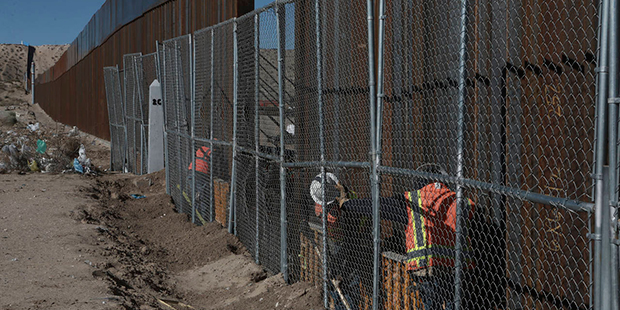 Workers continue work raising a taller fence in the Mexico-US border separating the towns of Anapra...