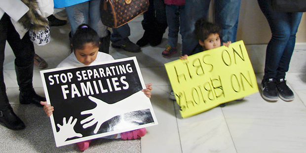 Children hold signs protesting an anti-sanctuary bill outside the House Education Committee meeting...