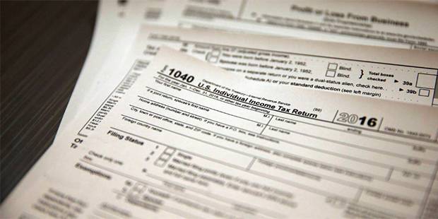 In this Jan. 14, 2017, photo, tax forms sit on a desk at the start of the tax season rush, inside t...