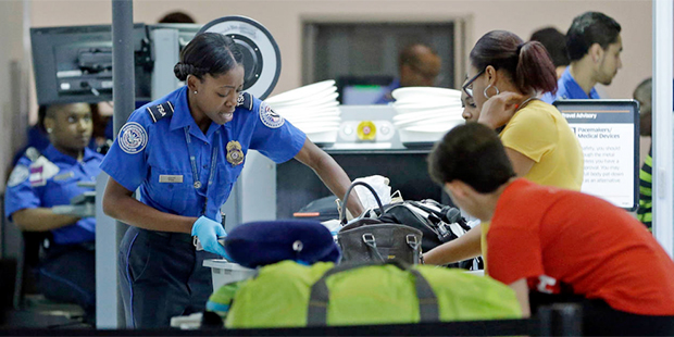 A Transportation Security Administration officer checks travelers luggage to be screened by an x-ra...