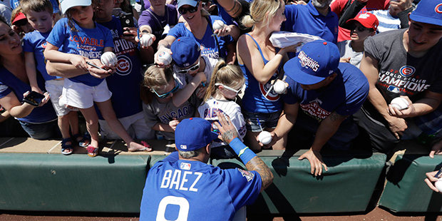 Chicago Cubs' Javier Baez gives autographs to fans before a spring training baseball game against t...