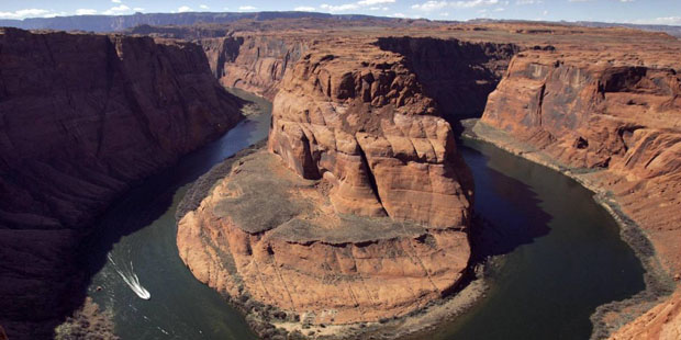 Boats skirt the shore at the Colorado River's Horseshoe Bend, downstream from the Glen Canyon Dam, ...