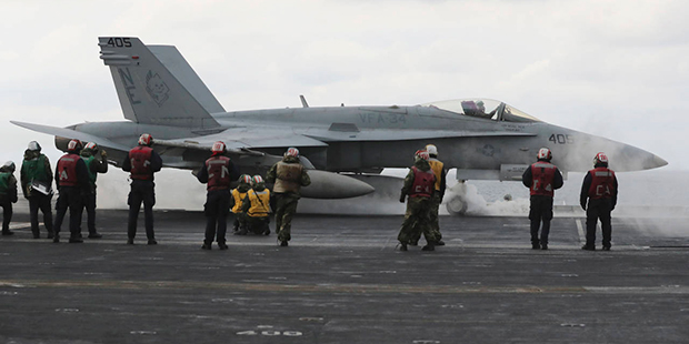 A F/A-18 fighter prepares to take off from the deck of the Nimitz-class aircraft carrier USS Carl V...