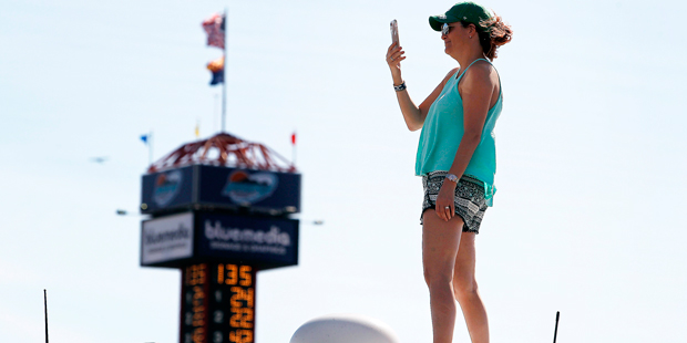 A race fan stands on her RV as she takes pictures with her cell phone during practice for a NASCAR ...