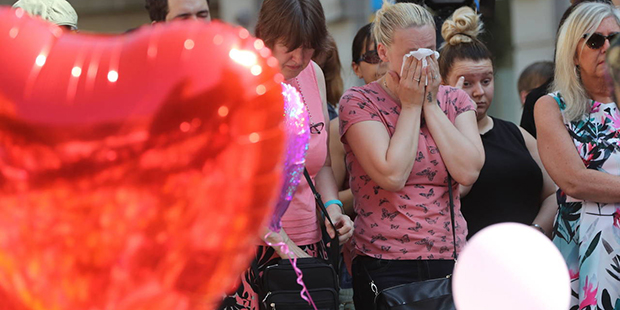 A woman reacts as people look at tributes in a square in central Manchester, England, Thursday, May...