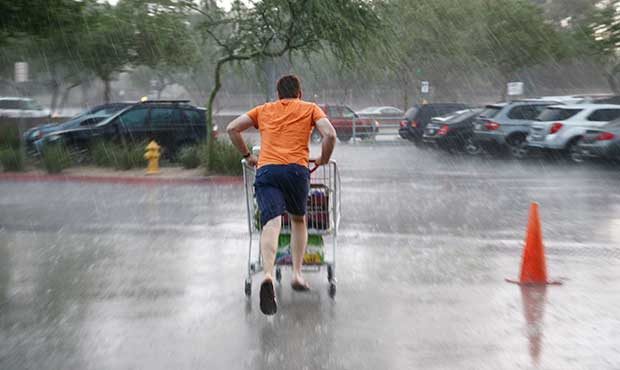 A shopper pushes a cart as he runs to his vehicle during a storm in Phoenix on Saturday, Sept. 27, ...