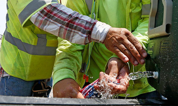 Crew members building the Loop 202 South Mountain Freeway, Art Singleterry, left, helps Paul Anger,...