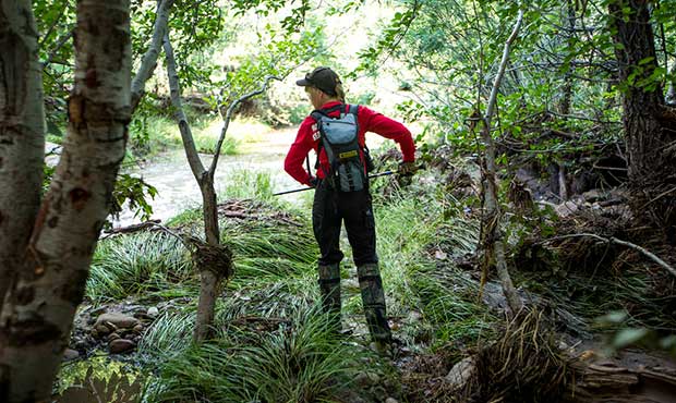 A Navajo County rescuer uses her walking stick to sift through debris in Tonto National Forest, Ari...