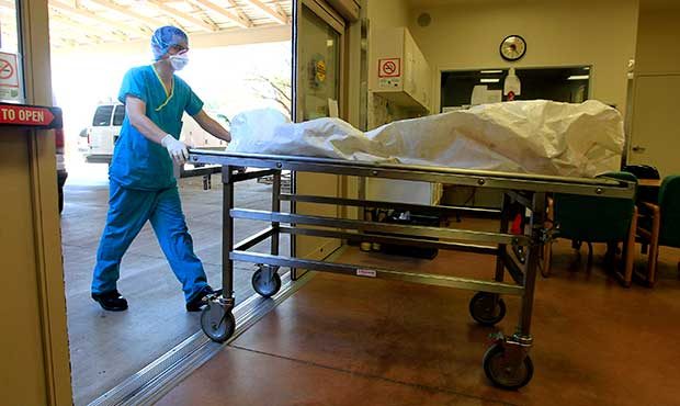 In this Aug. 10, 2012 photo, a morgue staff member brings in the body of a suspected illegal immigr...