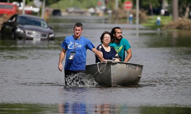 A man leads a boat with through a neighborhood inundated by floodwaters from Tropical Storm Harvey ...