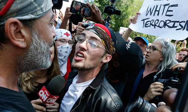 FILE - In this Aug. 19, 2017 file photo, a supporter of President Donald Trump, center, argues with...