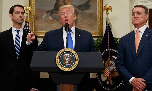 President Donald Trump, flanked by Sen. Tom Cotton, R- Ark., left, and Sen. David Perdue, R-Ga., sp...