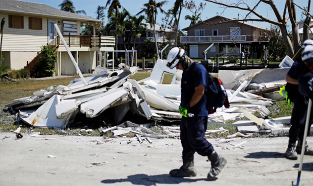 A member of the Arizona Task Force 1 search and rescue team walks by debris from a home as they kno...