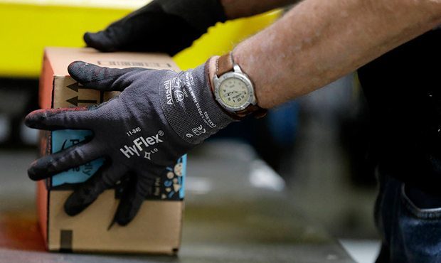 FILE - In this Tuesday, Aug. 1, 2017, file photo, an employee packages a product at the Amazon Fulf...
