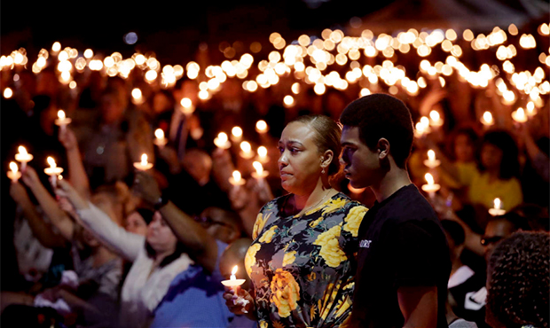 Veronica Hartfield, stands with her son, Ayzayah Hartfield during a candlelight vigil for her husba...