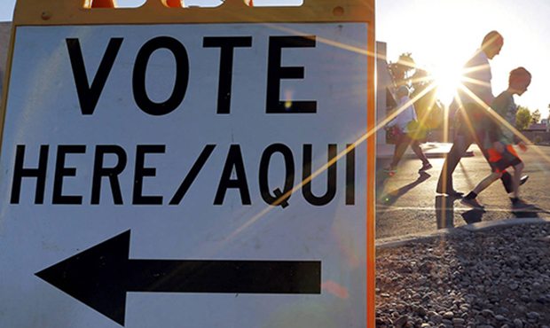 Voters come and go near a polling station at sunrise in Arizona's presidential primary election, Tu...