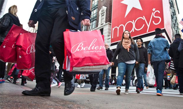 FILE - In this Nov. 27, 2015, file photo, shoppers carry bags as they cross a pedestrian walkway ne...