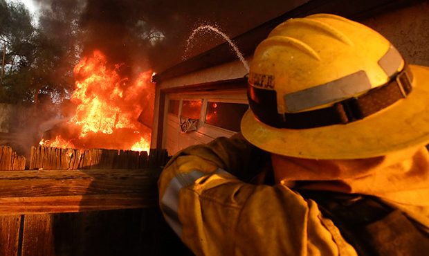 A Los Angeles County firefighter puts water a burning house in a wildfire in the Lake View Terrace ...