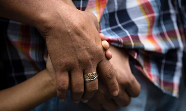 Alma Lopez holds her son Javier's and husband Javier Flores Garcia's hands during a news conference...